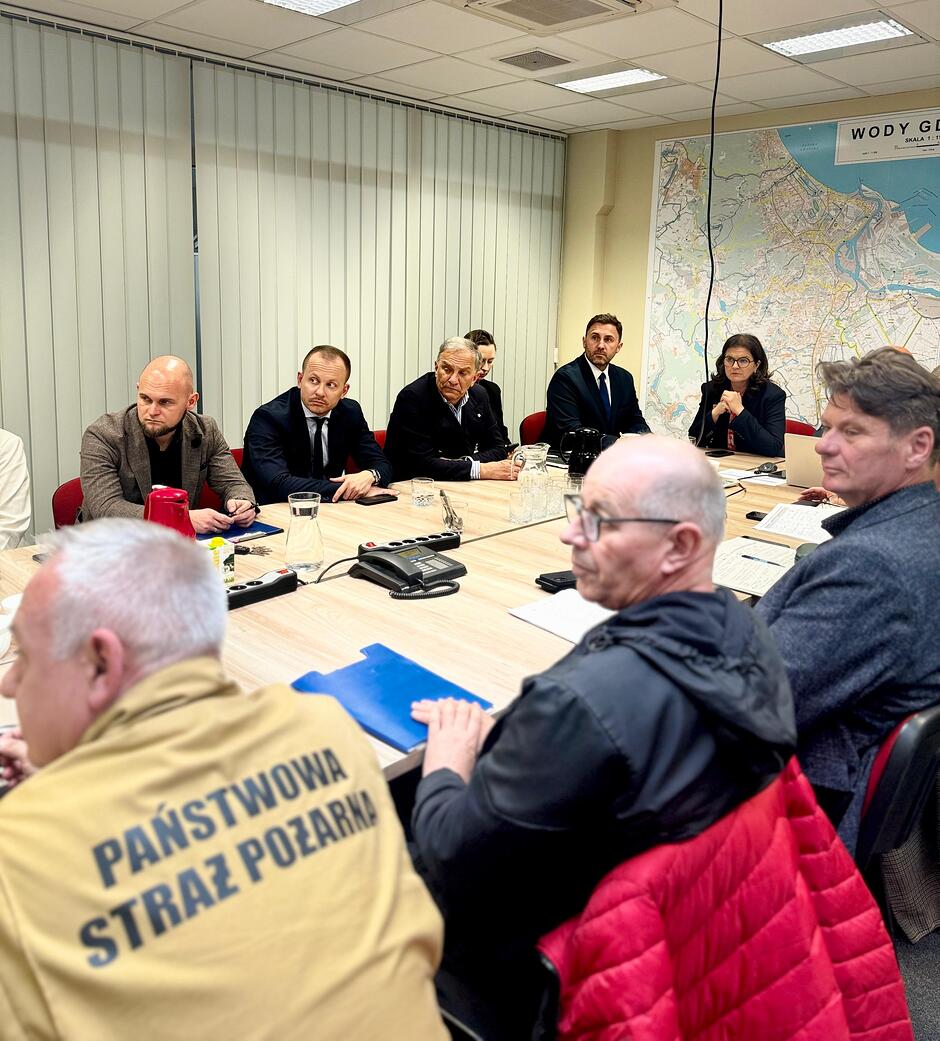 na zdjęciu kilka osób siedzi przy dużym stole ustawionym w kształcie litery u