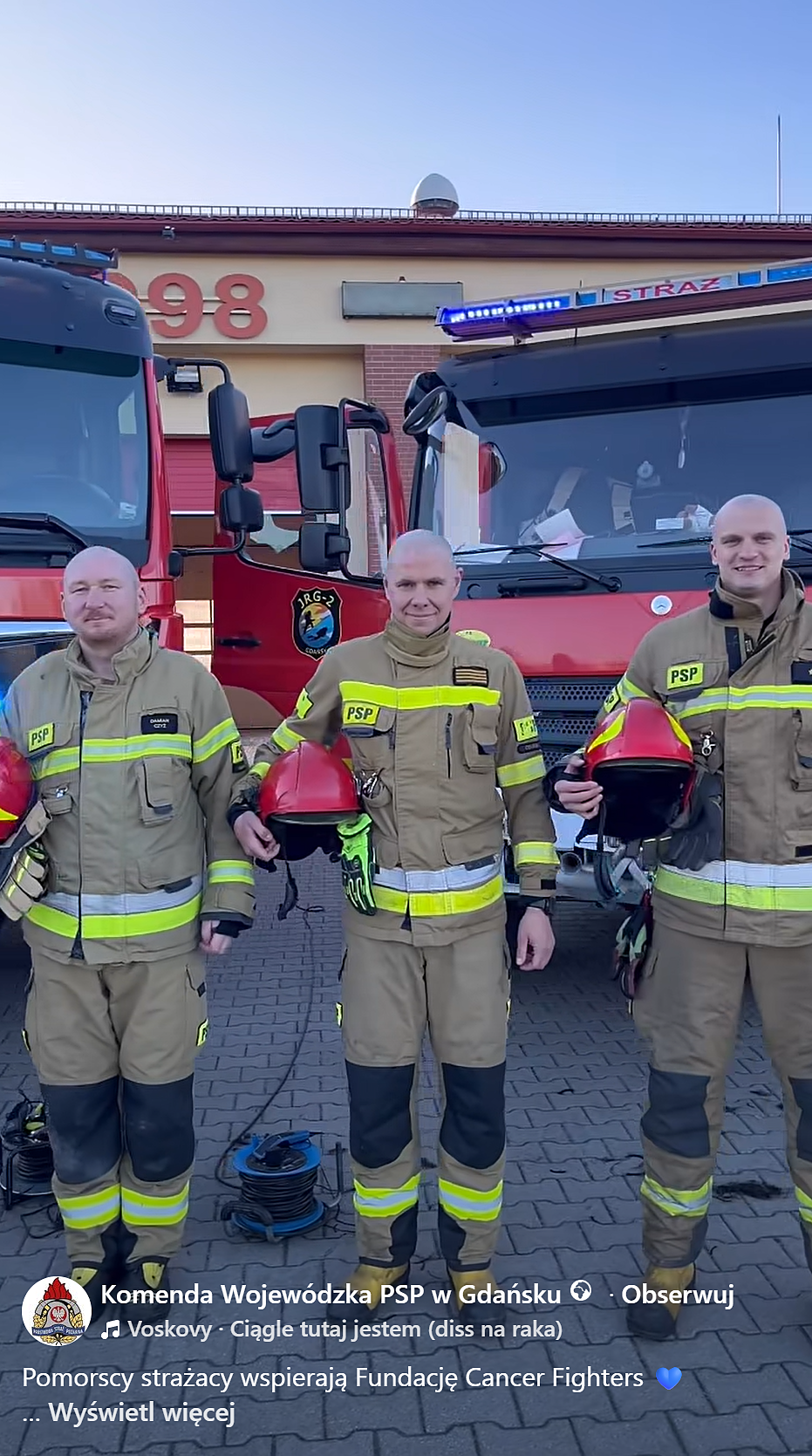 Łysi strażacy na tle wozu strażackiego