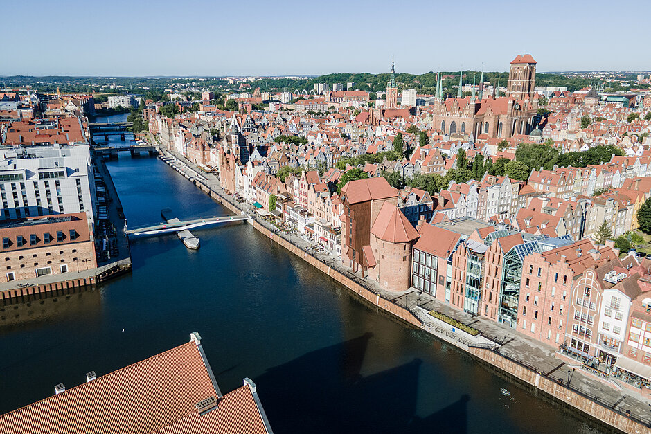 na zdjęciu z drona widać stare i główne miasto gdańska, w tym gęstą zabudowę kamieniczek i zabytkowy żuraw nad rzeką