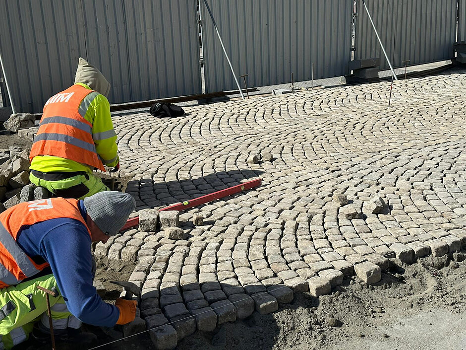 na zdjęciu dwóch robotników układających nowy bruk