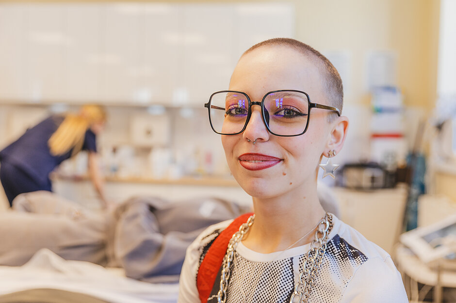 Dziewczyna w ogoloną głową uśmiecha się do aparatu 