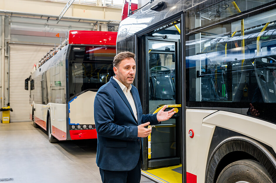 Prezydent Borawski na tle autobusów w hali produkcyjnej