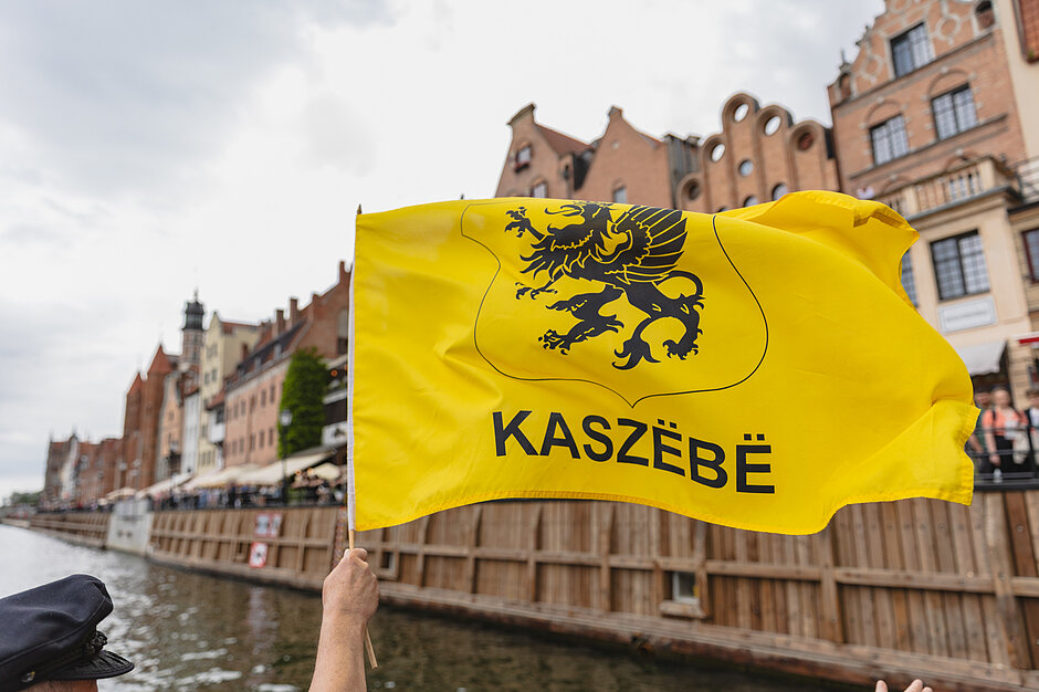 Żółta flaga z czarnym gryfem i napisem Kaszebe