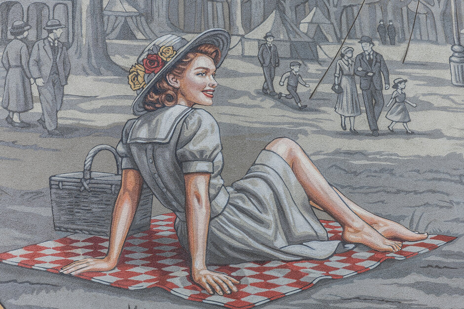 Mural przedstawia uśmiechniętą kobietę w eleganckim kapeluszu z kwiatami, która odpoczywa na kocu piknikowym w kratkę. W tle widać czarno-białą scenę z spacerującymi ludźmi oraz namiotami, co nadaje całości charakter dawnej epoki.