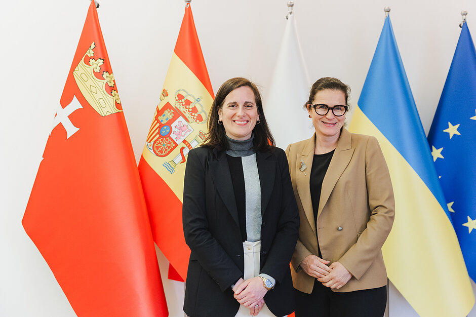 Dwie kobiety wspólnie pozuja do zdjęcia na tle flag obu państw, a także flagi gdańskiej i flagi Unii Europejskiej