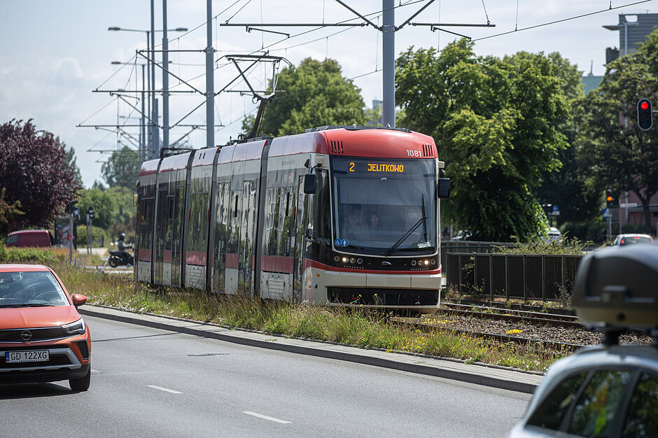 Tramwaj na ulicy Chłopskiej. W tle zielone drzewa. 