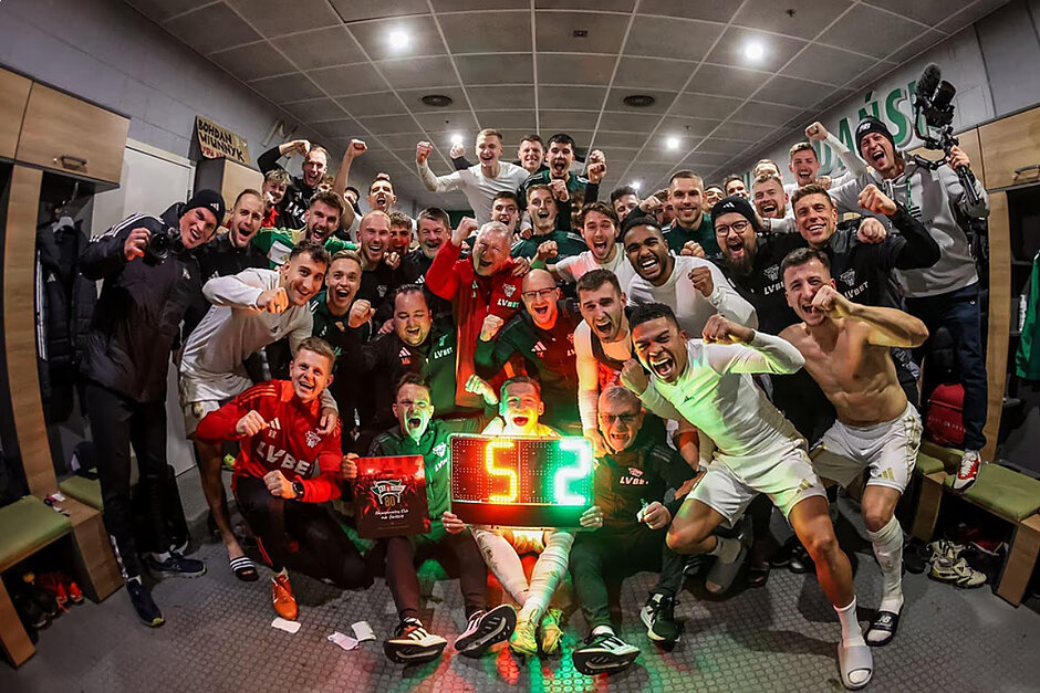 Grupa około 30 rozradowanych w większości młodych mężczyzn, w strojach sportowych entuzjastycznie pozują do wspólnego zdjęcia 