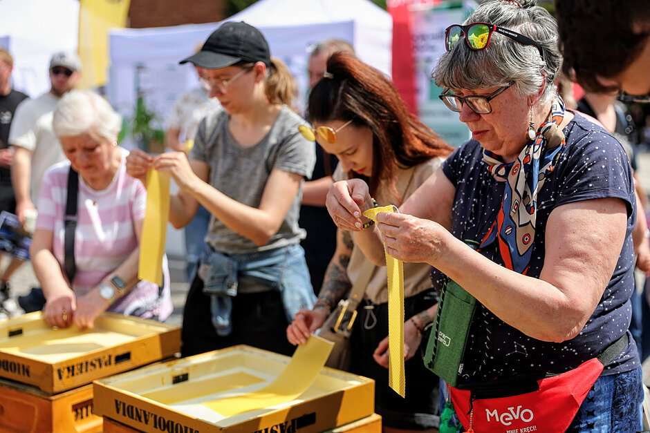 Kilka kobiet zwija plastry wosku pszczelego