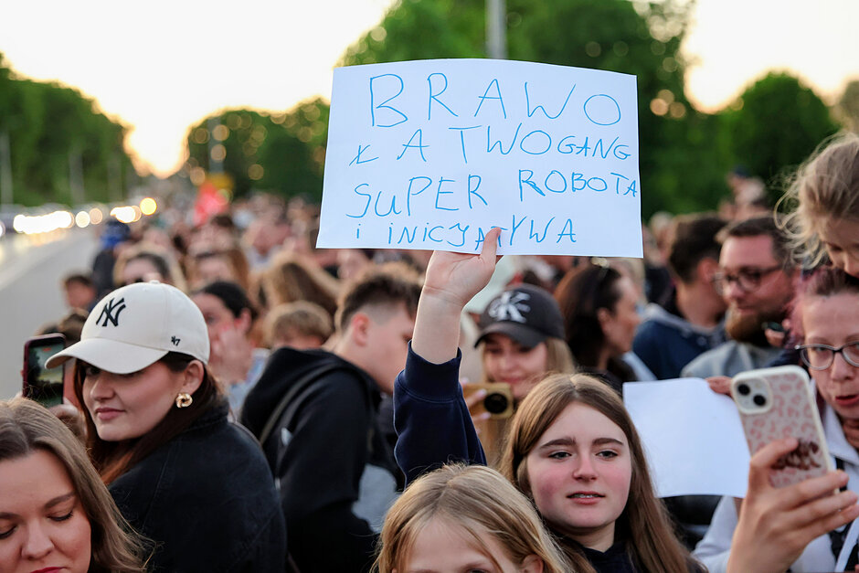 Grupa osób, głównie dziewcząt - jedna z nich trzyma kartkę z napisanymi gratulacjami dla Łatwoganga