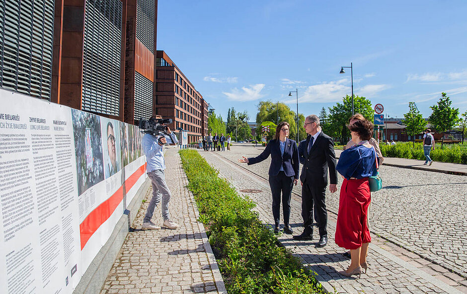 Andrzej Poczobut z grupą innych osób ogląda pod gołym niebem wystawę poświęconą walceo wolną Białoruś