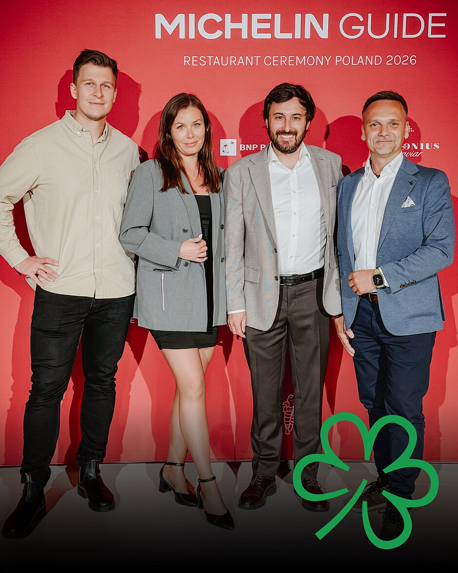 Jedna kobieta i czterech mężczyzn pozuje do zdjęcia na tle czerwonej ścianki z napisem Michelin Guide.