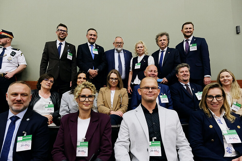 Grupa osób pozuje do zdjęcia w ławach sejmowych