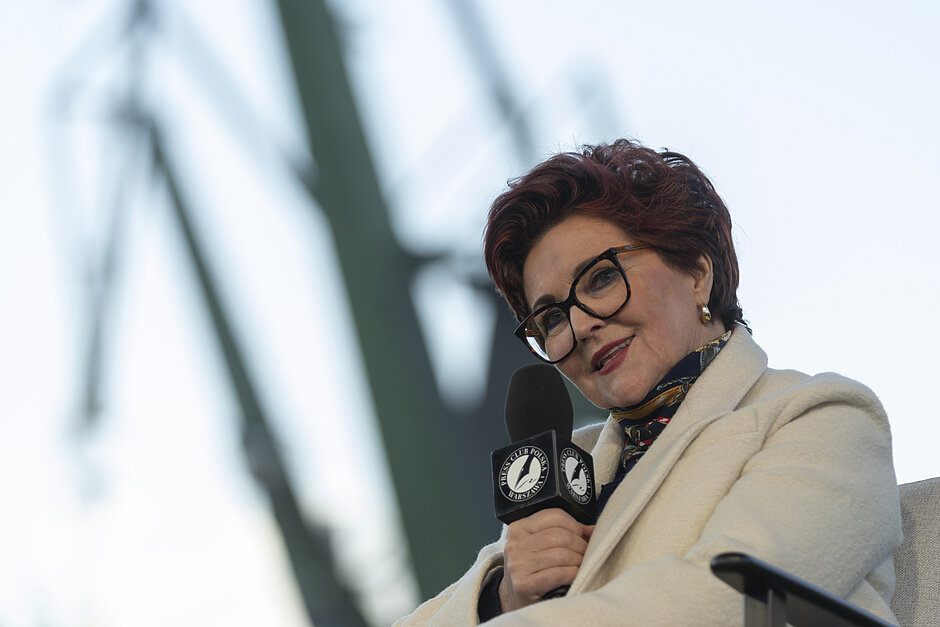 na zdjęciu jolanta kwaśniewska na tle stoczniowych dźwigów