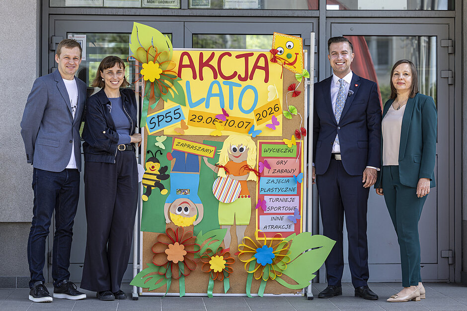 Dwie kobiety i dwóch mężczyzn pozuje do zdjęcia obok planszy z napisem "Akcja Lato 2026".