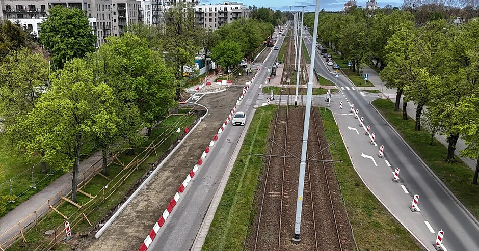 Zdjęcie z lotu ptaka, widok na dwupasmowa jezdnię z torowiskiem pośrodku.