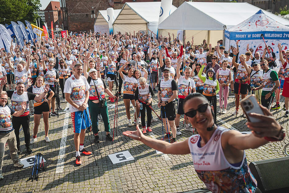 27. Bieg po Nowe Życie - rozgrzewka. Grupa ludzi w sportowych ubraniach rozgrzewa się przed biegiem 