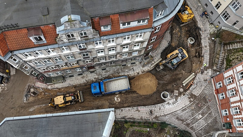 Widok z góry na rozkopaną ulicę, widoczna też koparka