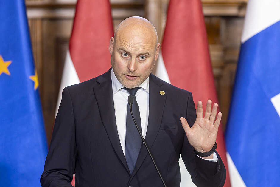 Łysy mężczyzna o okrągłej twarzy, w wieku średnim. Przemawia