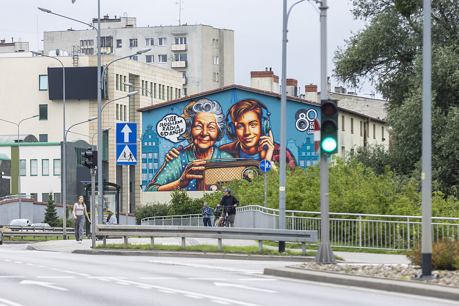 Mural z młodym chłopakiem i babcią słuchającymi radia na starym domu w mieście.