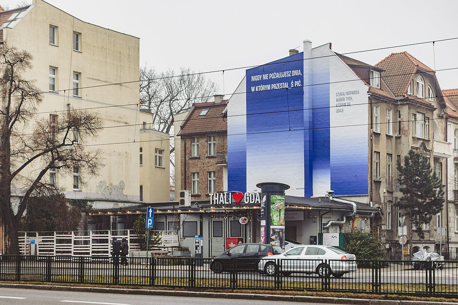 Stonowany mural w niebieskich kolorach z przesłaniem antyalkoholowym na starym domu w starej dzielnicy miasta.