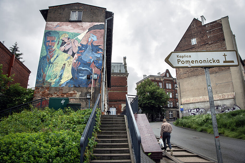 Mural upamiętniający Martina Luthera Kinga na starym domu w starej dzielnicy miasta, mija go kobieta.