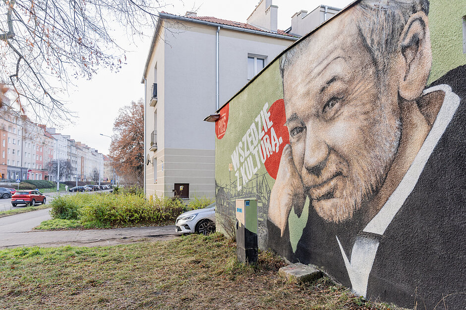 Mural z Mirosławem Baką na małym budynku w mieście.