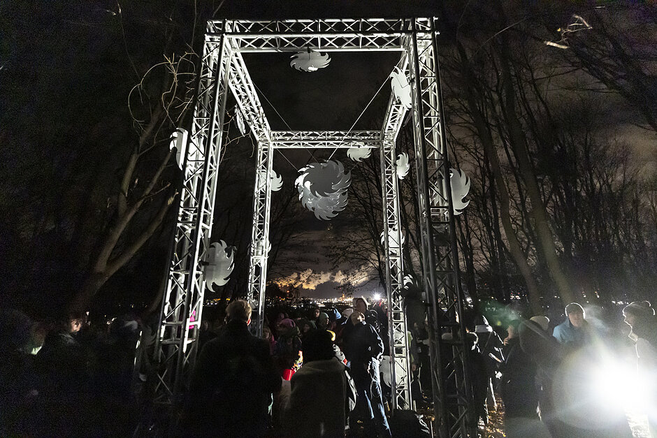 Ludzie przy instalacji artystycznej w mieście wieczorem.
