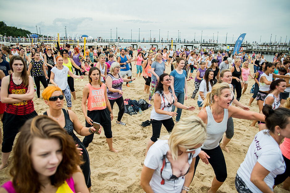 Grupa ludzi ćwiczy Zumbę na plaży