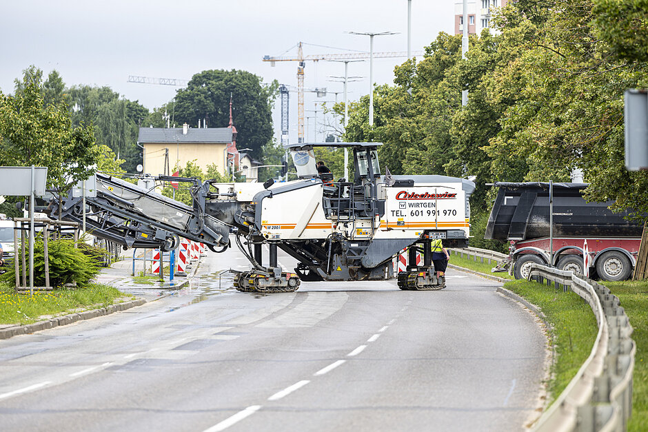 na zdjęciu duża maszyna budowlana na kółkach, stoi na jezdni