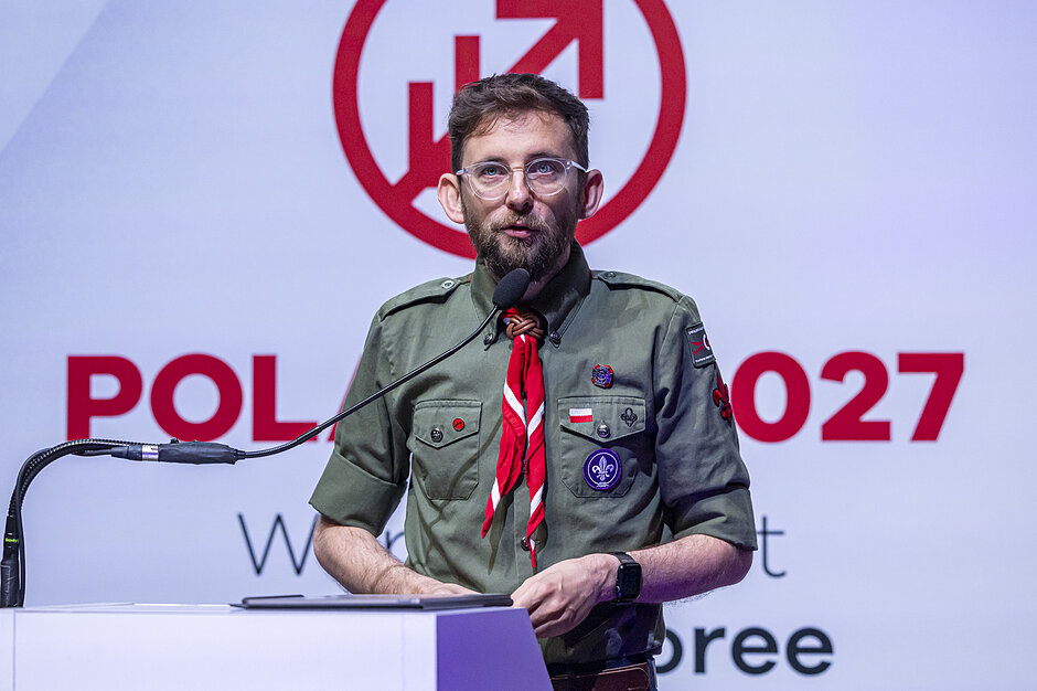 Wymieniony harcerz, mężczyzna w okularach, przemawia ze sceny