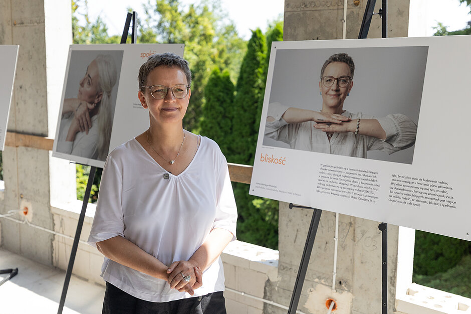 Wernisaż wystawy Między diagnozą a siłą. Anna Marlęga-Woźniak stoi obok swojego portretu 