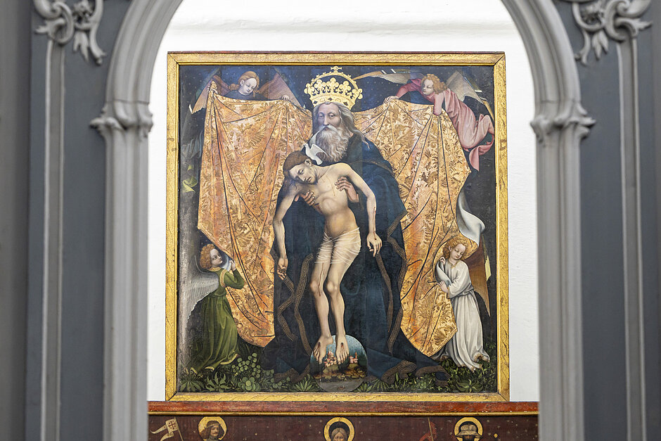 Scena religijna, przedstawiająca Jezusa Chrystusa na krzyżu. Obraz jest oprawiony w ozdobny łuk ze złotą granicą i ustawiony na białym tle. Jezus jest pokazany w środku ma na sobie niebieski szlafrok i długą białą brodę i wąsy. Jego ciało jest pokryte złotym szlamem, który jest zasłonięty na jego ramionach. Po obu stronach Jezusa są dwaj aniołowie, po jednej z nich, trzymając się za ręce i patrząc na Niego. 
