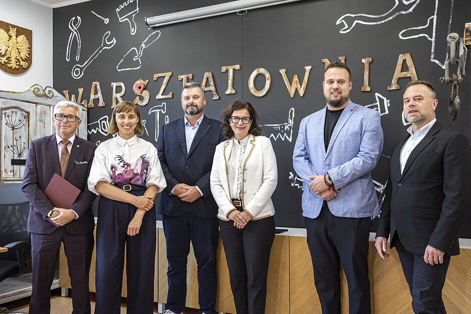 na zdjęciu czterech mężczyzn i dwie kobiety w średnim wieku, wszyscy stoją w rzędzie, pozują do zdjęcia