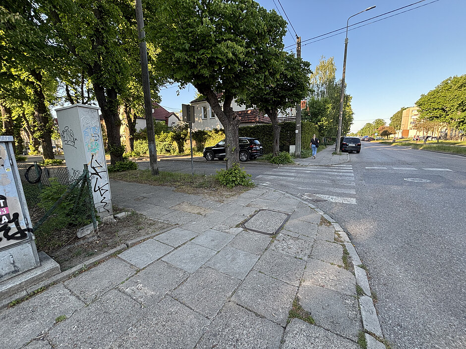 fragment jezdni i chodnika, w tle budynek