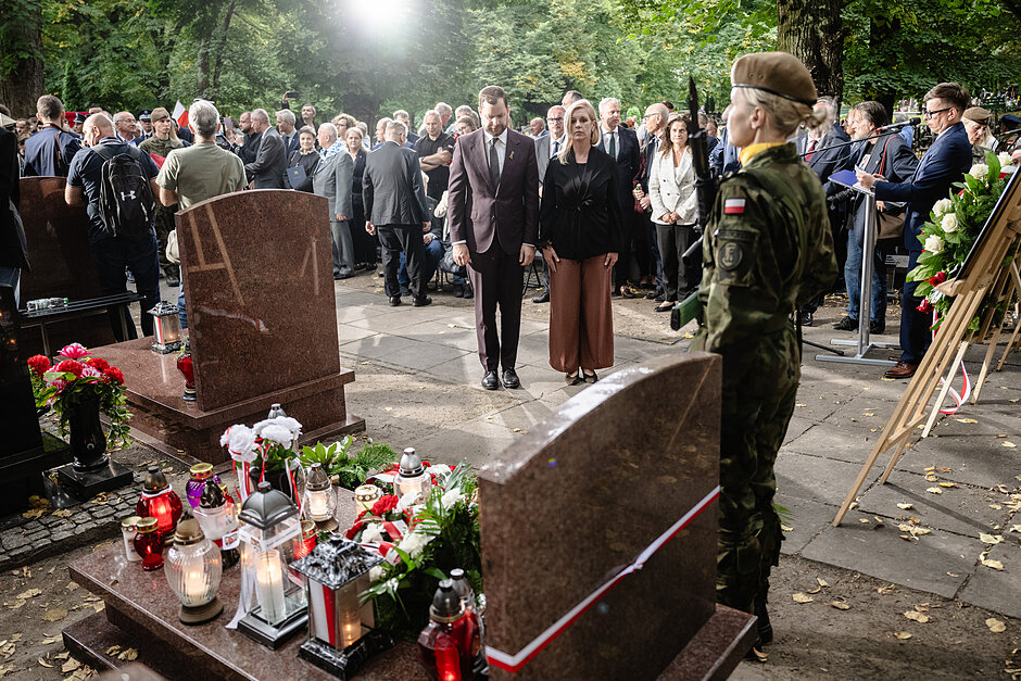 Kobieta i mężczyzna składają na cmentarzu kwiaty przed grobami Inki i Zagończyka.