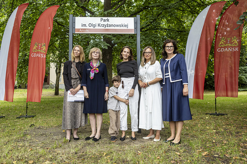 wymienione osoby stoją pod tablicą z napisem Park im.Olgi Krzyżanowskiej 