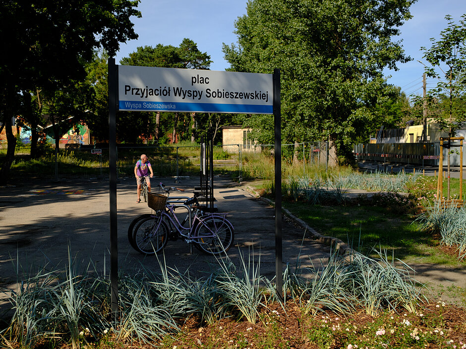 tablica z nazwą Plac przyjaciół wyspy sobieszewskiej, zieleń
