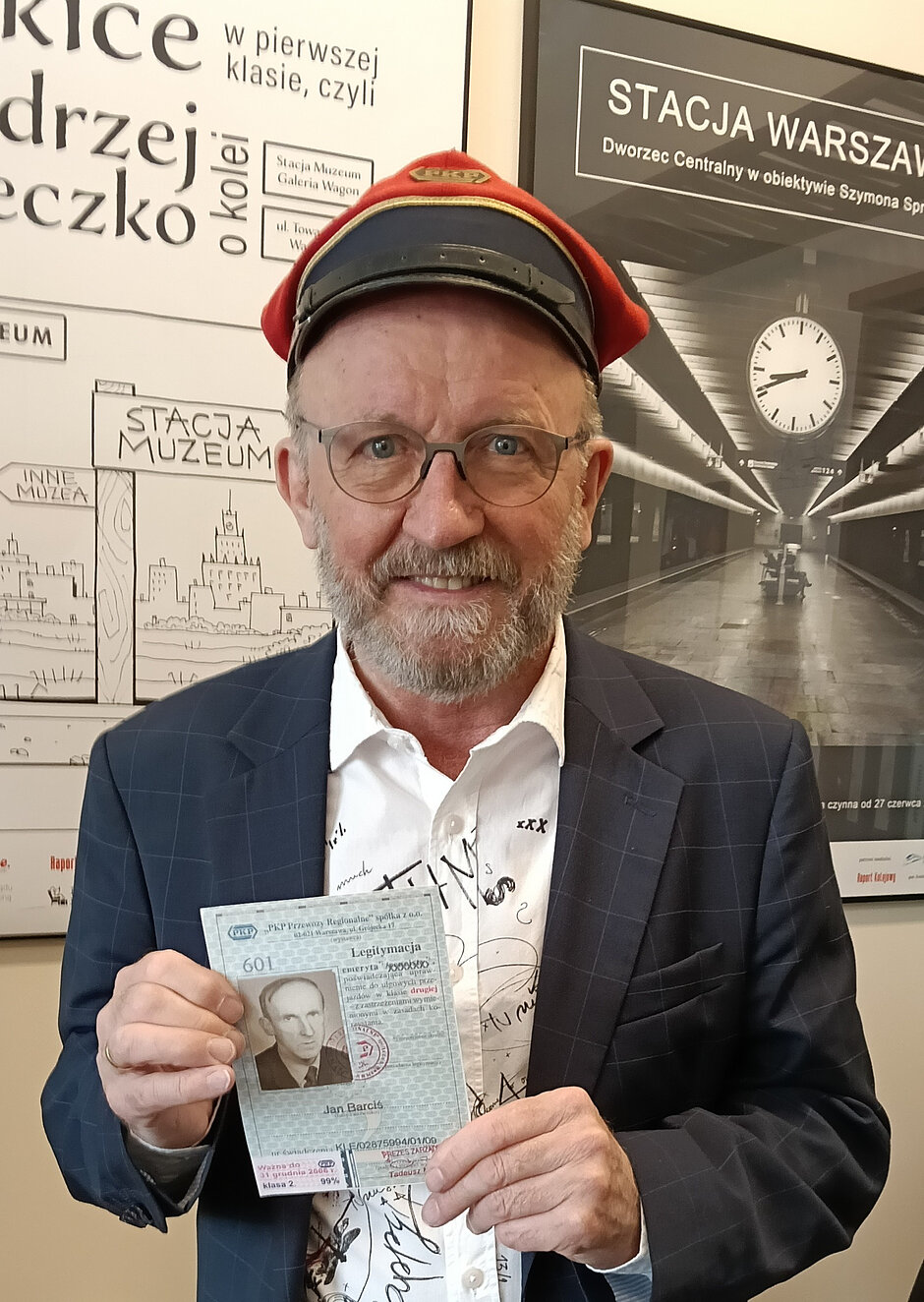 mężczyzna w średnim wieku w stroju konduktora prezentuje legitymację kolejarza swojego ojca