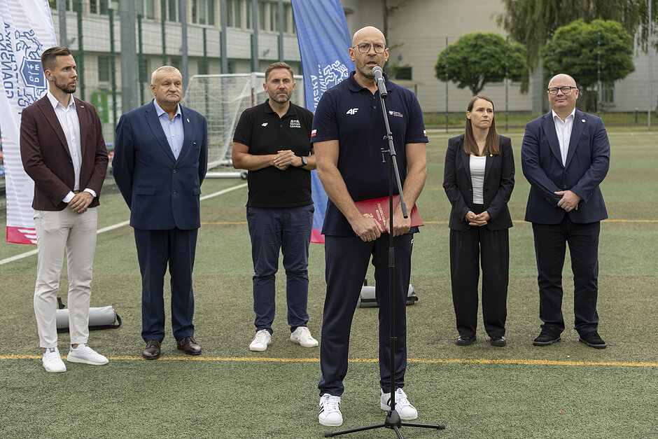 Zdjęcie grupy osób, które stoją na trawiastym boisku