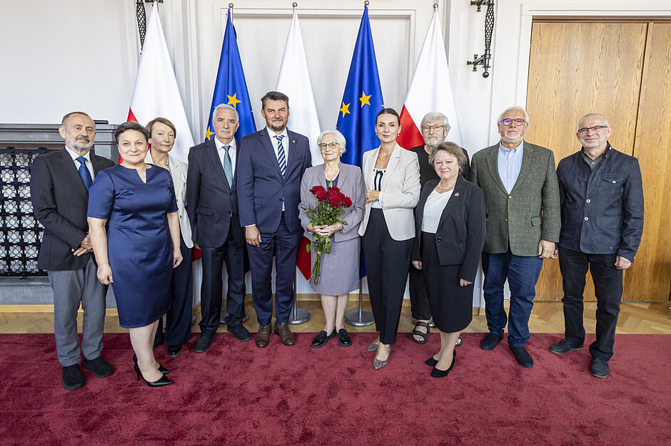 zdjęcie kilkunastoosobowej grupy ludzi na tle flag polski i unii europejskiej
