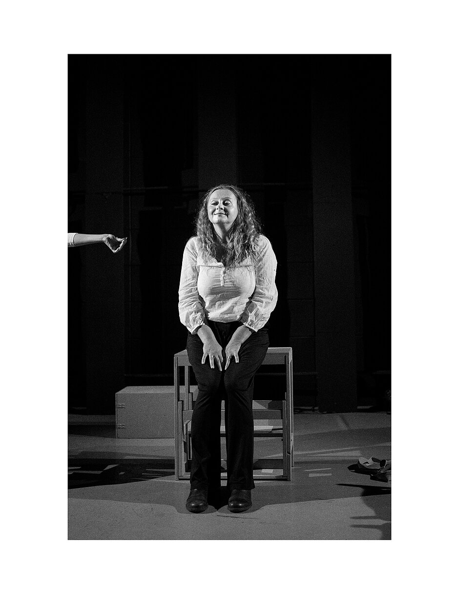 Portret kobiety na krześle na scenie teatru.