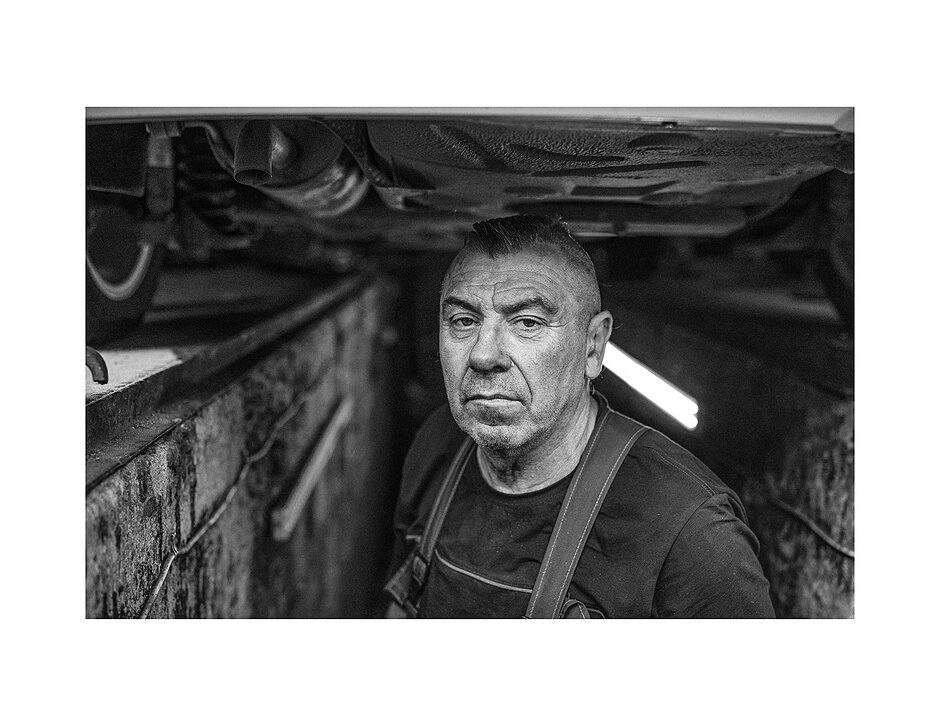 Portret mężczyzny mechanika pod samochodem w kanale.