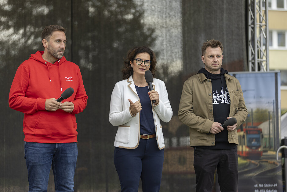 Trzy osoby z mikrofonami, na scenie