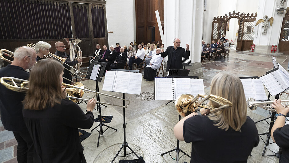 Kilka osób gra na instrumentach dętych, we wnętrzach kościoła