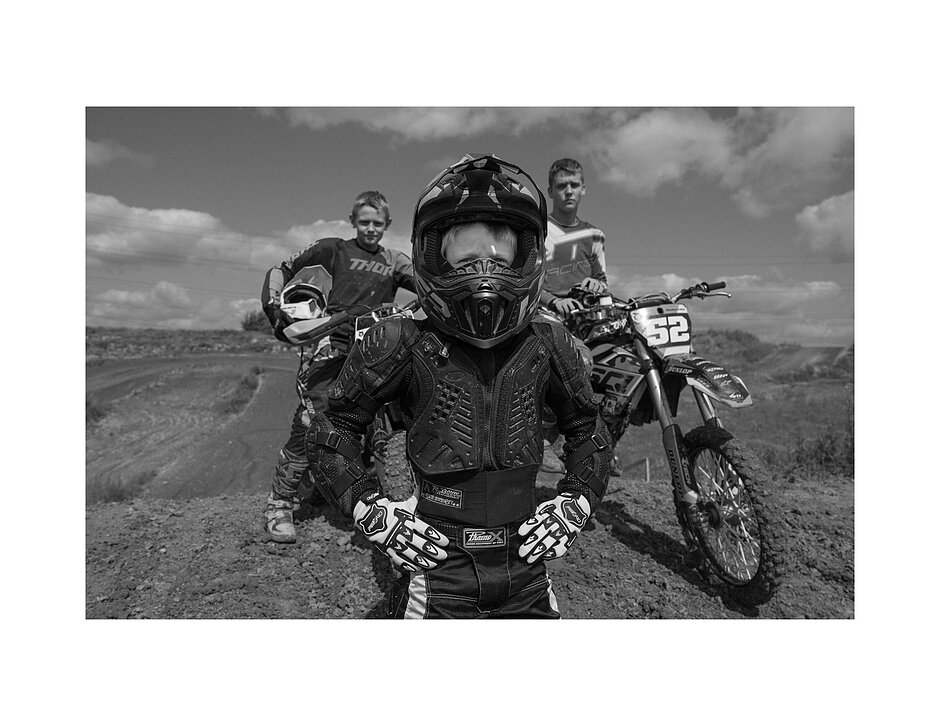 Trzech chłopców w strojach motocrossowych przy motocyklu