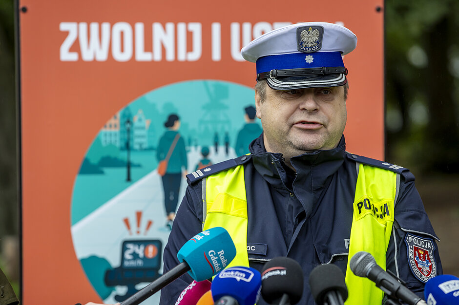 policjant w służbowym stroju mówi do mikrofonu