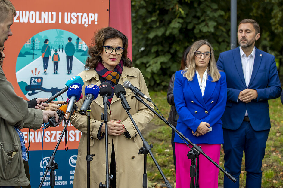 wymienione osoby na zdjęciu, za nimi grafika z napisem Zwolnij i ustąp pieszym