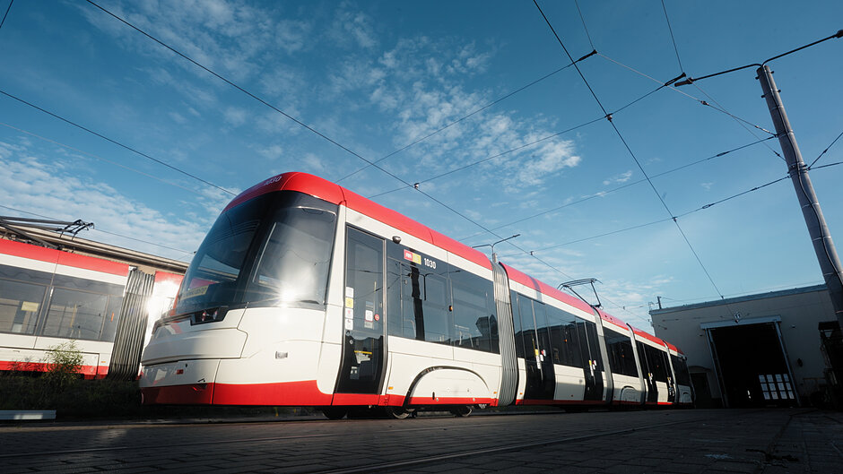dwa tramwaje, stojące jeden za drugim, oba biało czerwone