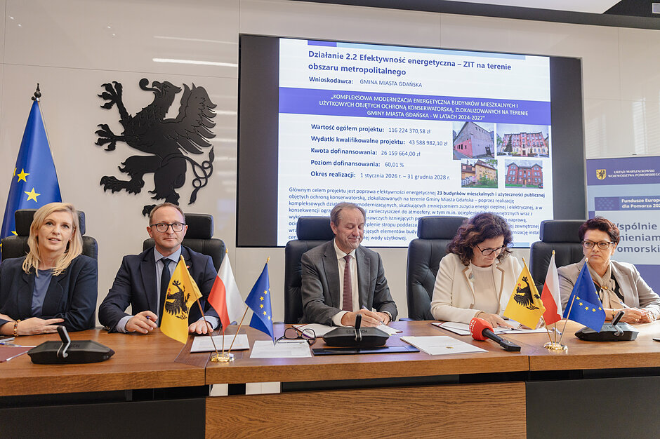Zdjęcie podczas konferencji. Grupa ludzi siedzi przy stole