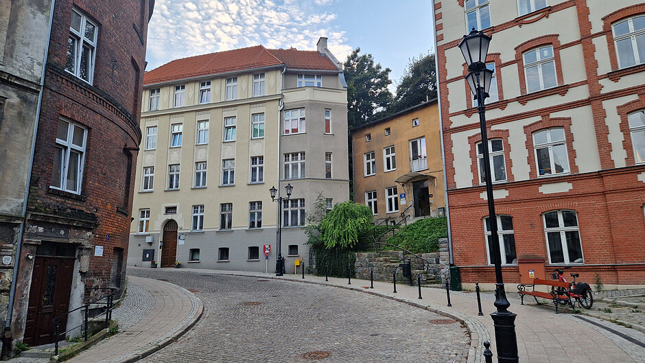 Widok z dołu na zakręt na ul. Biskupiej. Z lewej stare kamienice, w środku i po prawej piękne wyremontowane